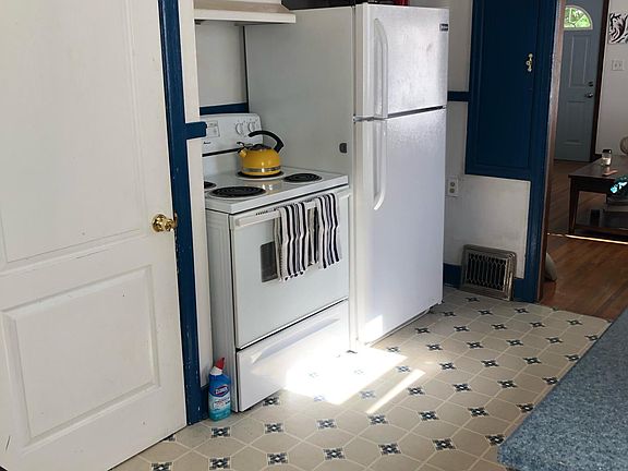 All appliances: stove, refrigerator, dishwasher. The white door leads from the kitchen to the basement.