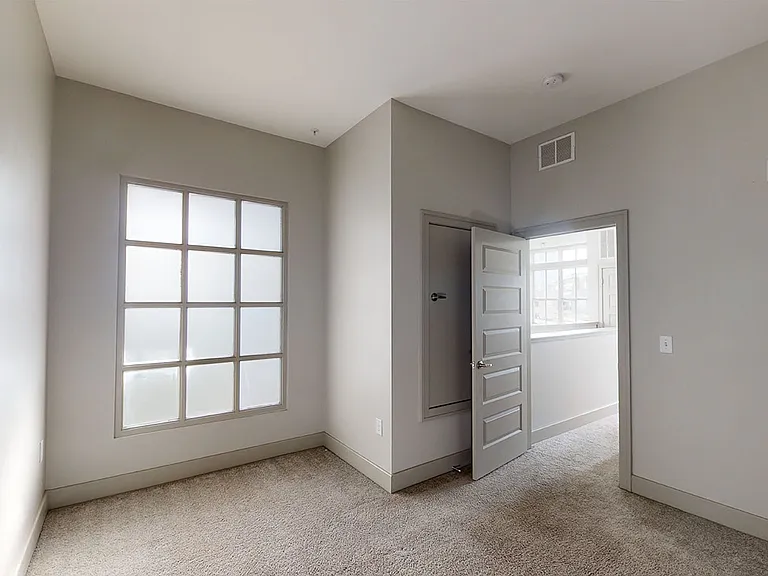 Spacious apartment bedroom with plush carpet flooring.