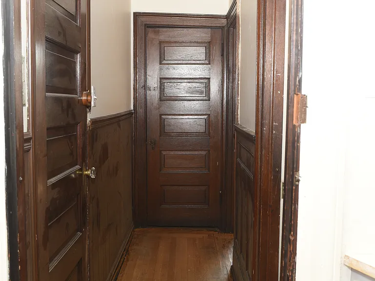 Charming interior hallway showcasing original hardwood floors, rich wood paneling, and beautifully preserved solid-wood doors.
