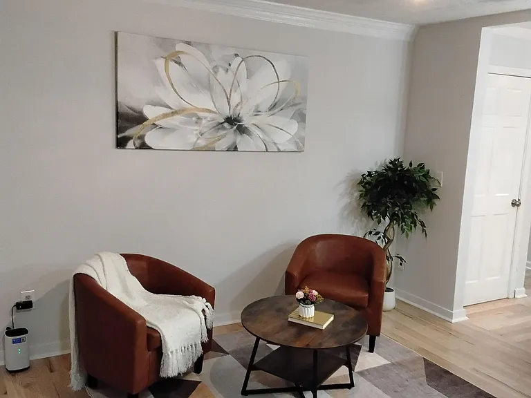 Comfortable shared living area with two lounge chairs, a coffee table, and ceiling fan, plus easy access to nearby rooms.