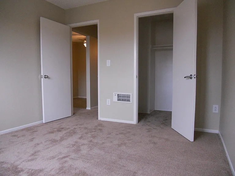 Carpeted bedroom with walk-in closet at Villa Pacific Apartments in Oceanside, California.