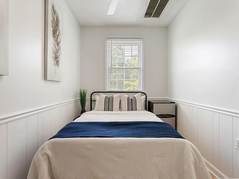 Private bedroom with a full bed, ceiling fan, window with blinds, and a convenient mini fridge for in-room snacks and drinks.