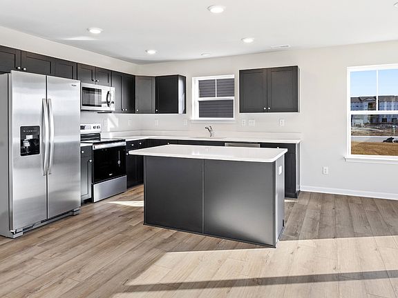 Island kitchen with dark gray cabinets in a DRB Homes Cranberry plan at the Village of College Park