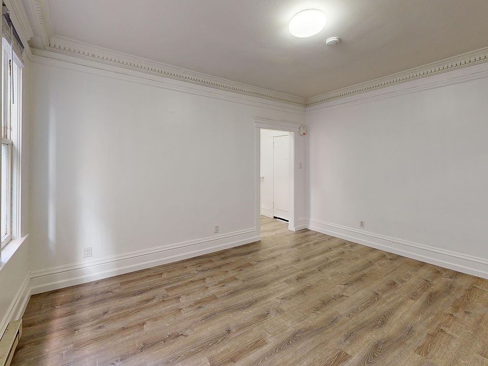 Sunlit room with a large window and wood-like flooring