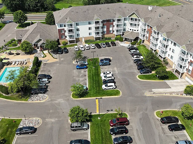 Aerial view of a charming suburban apartment community with lush green landscaping, spacious parking, and picturesque neighborhood surroundings.