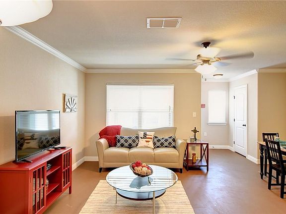 Downstairs Living Room has an entry hall closet, side door going to court yard, lots of windows, concrete flooring and ceiling fans