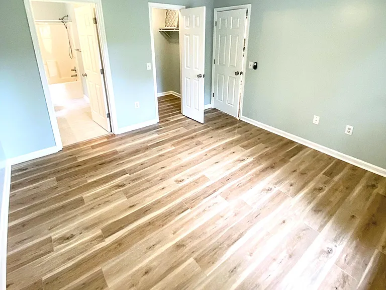 Main bedroom with door to bathroom on left and walk-in closet on right. Door to living room closed on the far wall.
