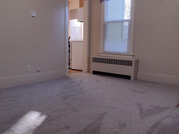Newly carpeted living room with high ceilings, ceiling fan, mini-blinds, and valances.
