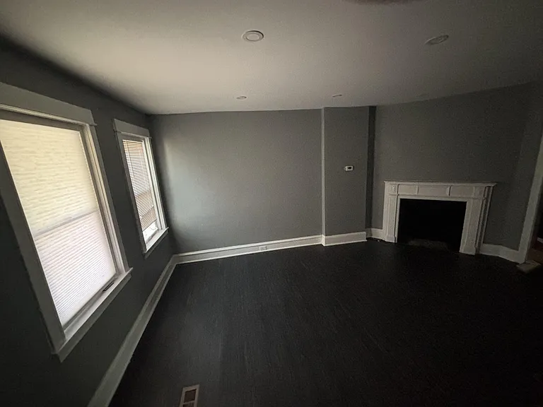 Spacious room with two windows for natural light and a decorative fireplace mantel, offering flexible layout options.