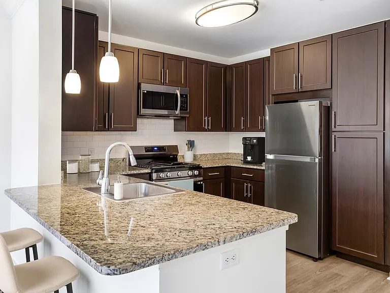 Classic Package kitchen with espresso cabinetry, beige speckled granite countertops, white tile backsplash, stainless steel appliances, and hard surface flooring