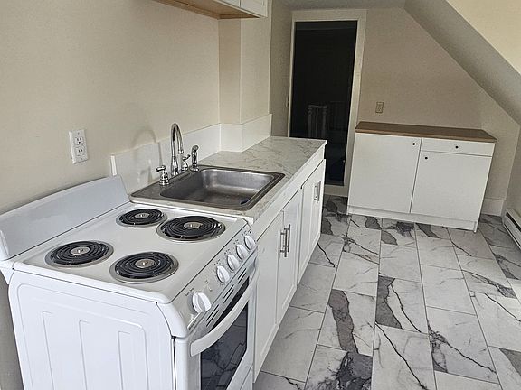Partial view of the kitchen area with door at rear leading to the central hallway