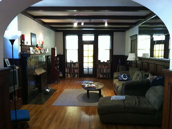 Large old style livingroom with original dark walnut wainscoting, stone fireplace and decorative beams