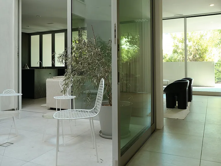 Indoor-Outdoor Living with Private Courtyard _ Enjoy tranquil mornings and evenings with direct access to a private outdoor courtyard. The sliding glass walls allow sunlight to cascade into the space, enhancing the serene ambiance.