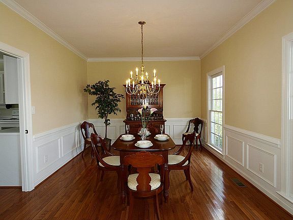Dining room features wainscotting, chair rail, crown molding, and hardwoods.