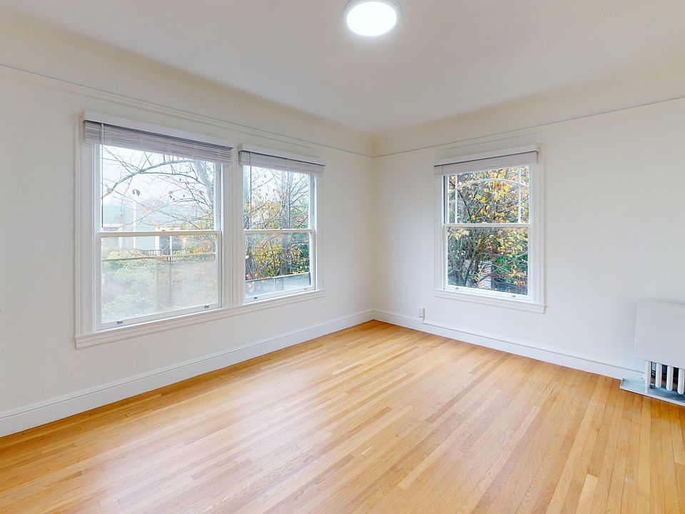 Sunlit room with a large window and wood-like flooring