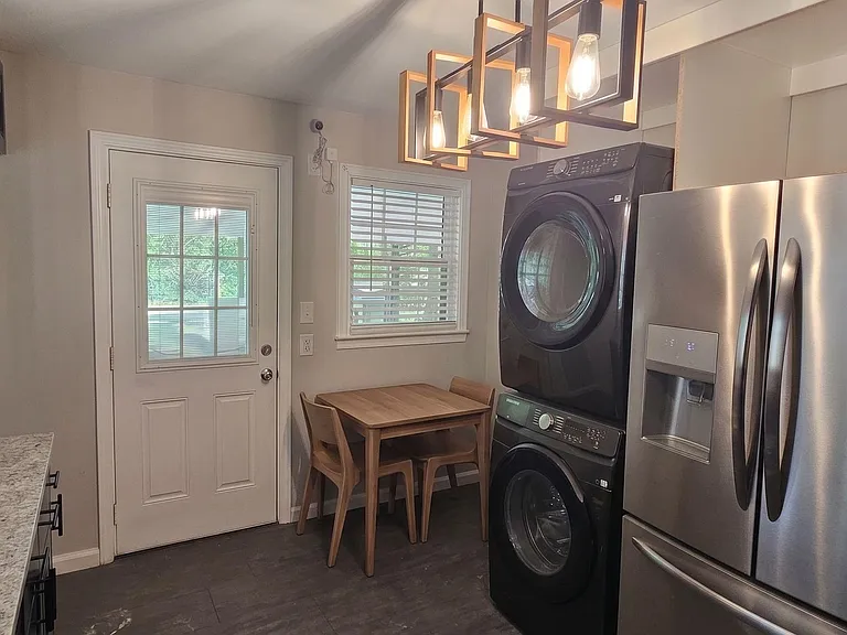 Eat-in kitchen nook with stainless refrigerator and in-unit stacked washer/dryer, plus a back door and window for airflow.