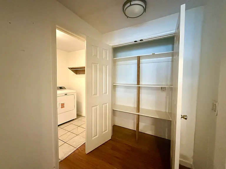 View of the open pantry, which is to the left of the kitchen cabinets and up a small step. Laundry room visible on the far left.