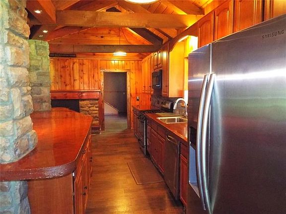 BEAUTIFUL OPEN KITCHEN WITH STAINLESS APPLIANCES, CONCRETE COUNTERS, KITCHEN ISLAND WITH LIGHTING WITH STONE COLUMNS AND FIREPLA