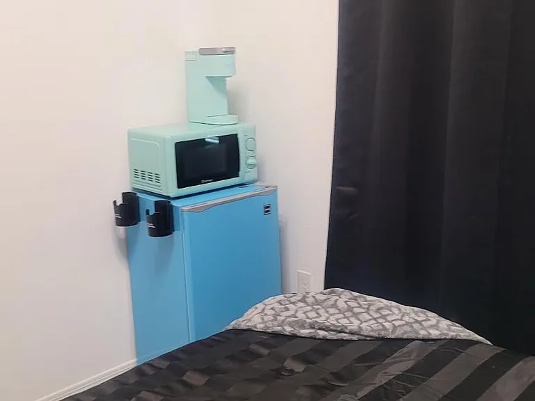 Compact bedroom with a bed and in-room mini fridge and microwave for added convenience.