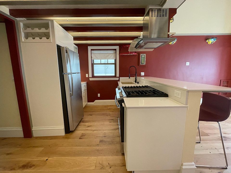 Kitchen with wide counter fitting four counter chairs. Lighting is done thoughtfully to enable multiple changing scenes. There is even a wine bottle shelf.