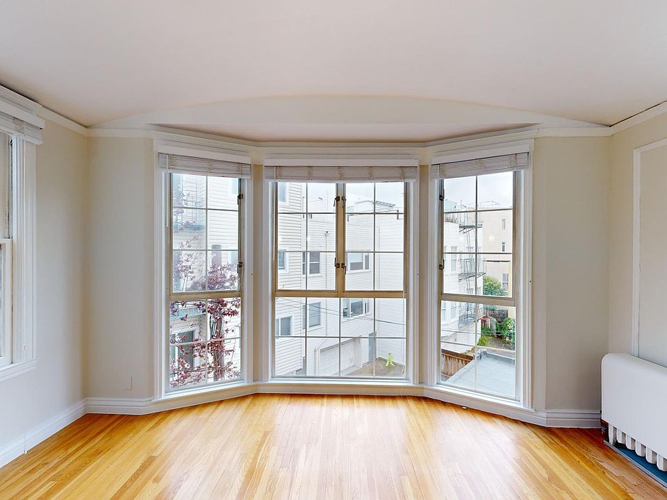 Spacious living room with large windows and wood-like floors