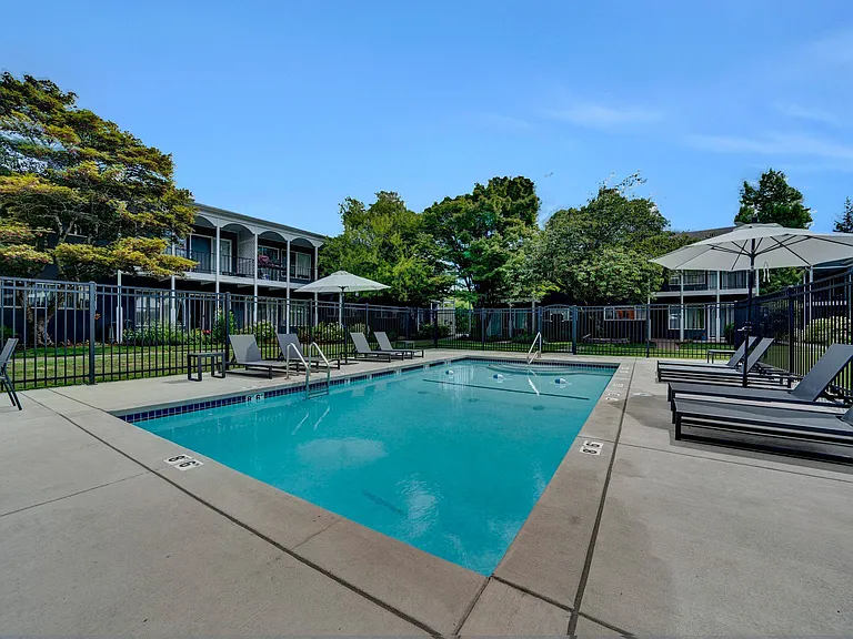 a swimming pool with lounge chairs and umbrellas in front of a building Sunset Station Apartments Portland Oregon