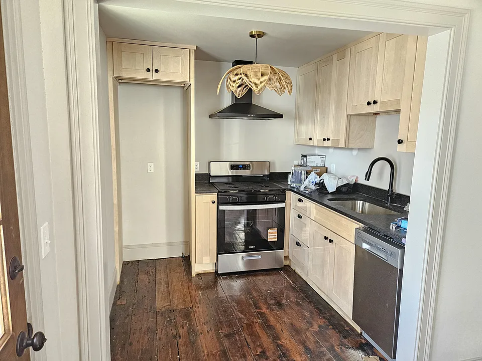 Kitchen with stainless fridge (not yet installed in photo), dishwasher, and stove with range hood