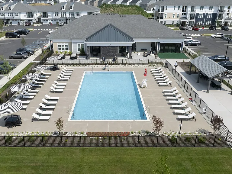 Luxurious apartment complex featuring a sparkling outdoor pool surrounded by chic lounge chairs and stylish umbrellas