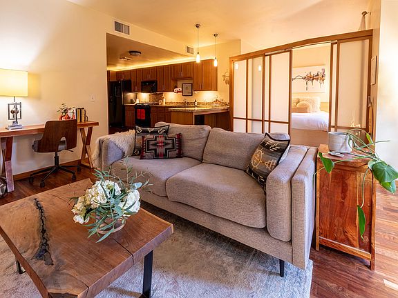 View from the french doors/patio, looking across living space, with kitchen on left and bedroom on right.