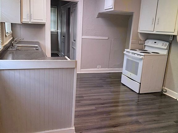 The kitchen, with the hallway that leads to the upstairs, the first bathroom, and the back door.