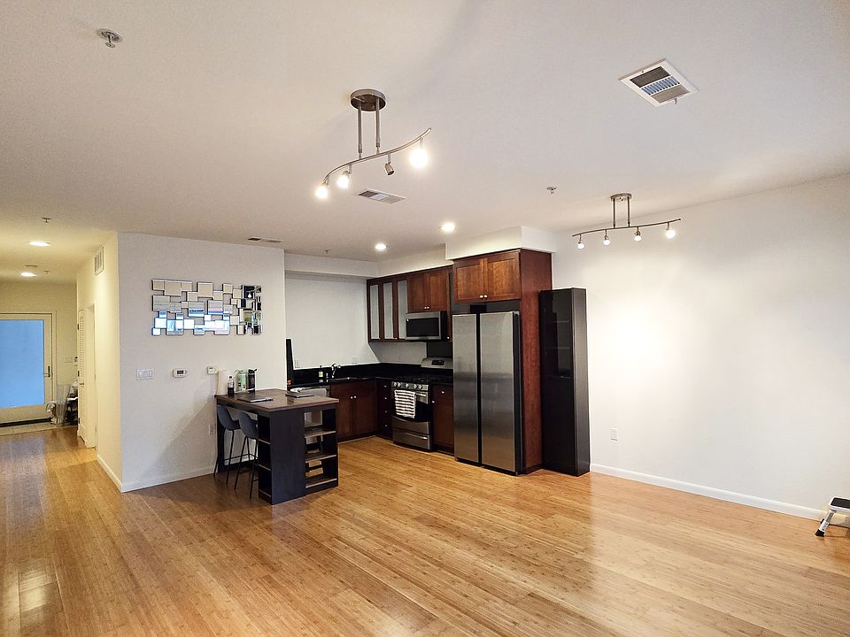 Living area with updated appliances and dining table w/ stools.
