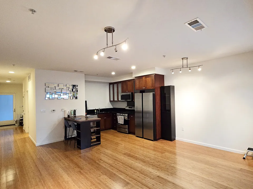 Living area with updated appliances and dining table w/ stools.