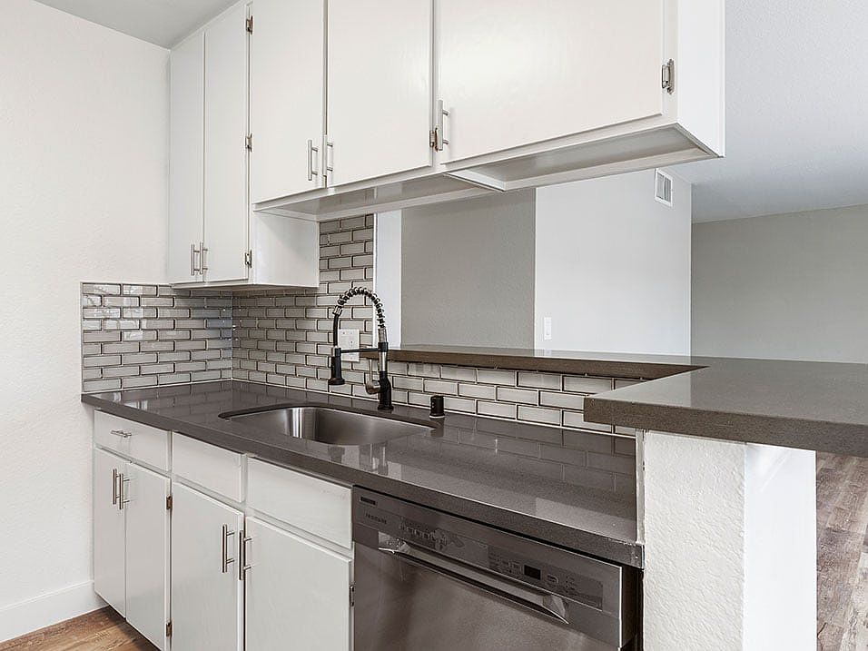 White tiled kitchen with stainless steel fixtures.