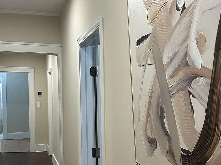 Clean, well-lit hallway with recessed lighting, neutral walls, and easy access to multiple rooms for convenient flow.