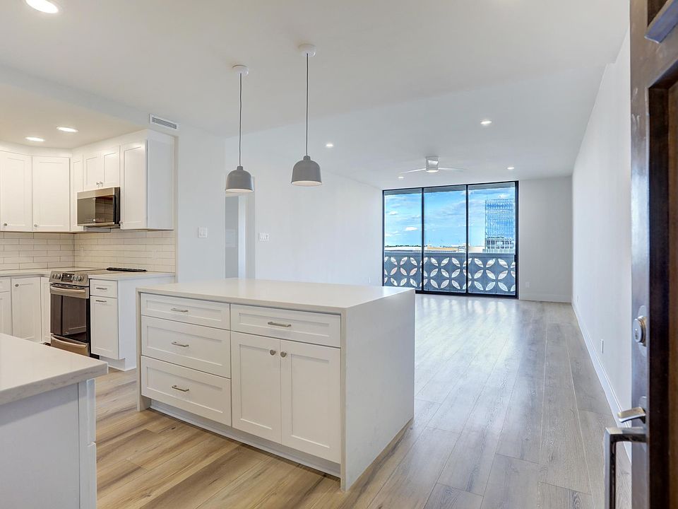 Island with breakfast bar with waterfall quartz countertops.
