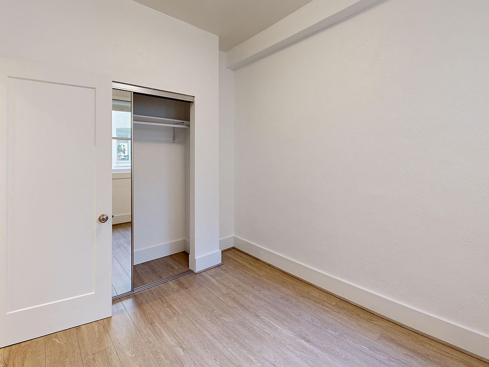 Bright bedroom with wood-like floor and a closet with mirror