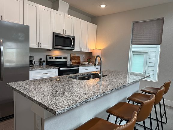 Open kitchen with a central island that serves as the main dining area, combining style and functionality in one space.

Granite countertops and stainless steel appliances add to the modern aesthetics of this home.
