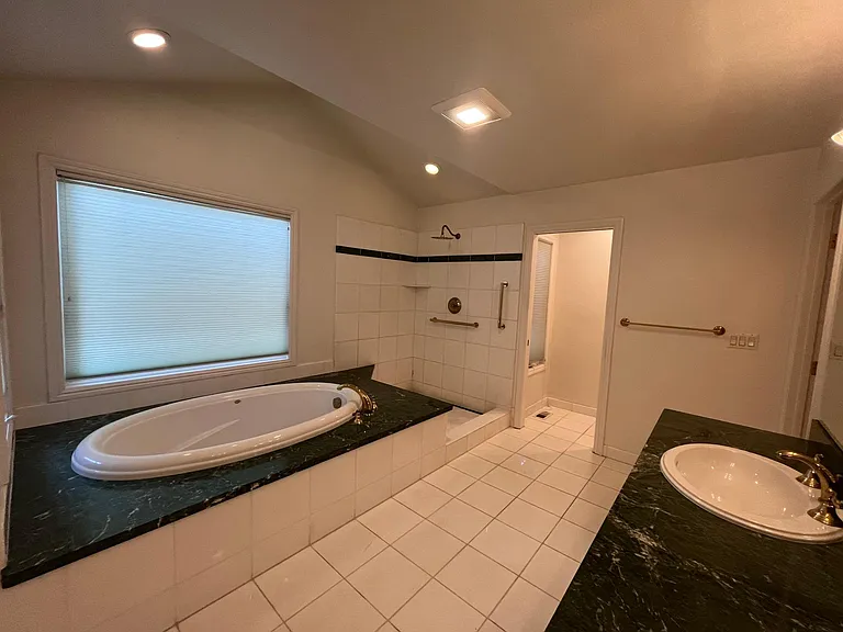 In-suite primary bathroom is tastefully-appointed with dual sinks, Jacuzzi tub and shower stall.