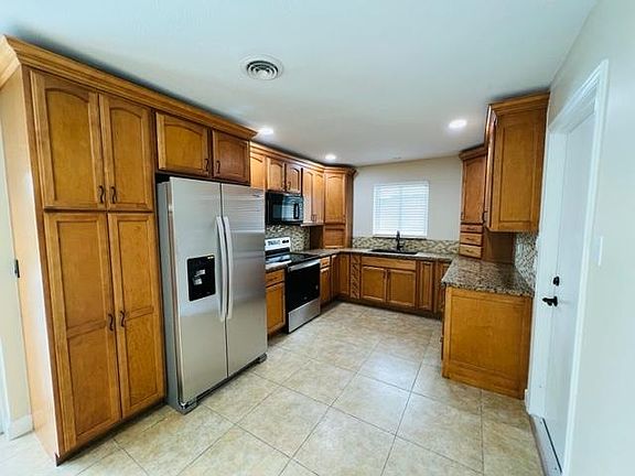 Kitchen equipped with custom wood cabinets, recessed LED lights, Granite counters, and brand new S/S appliances.