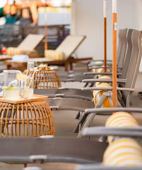 Resort-style outdoor space with a heated pool, hot tub, sun loungers with umbrellas, and cozy seating. Perfect for relaxing, sunbathing, or enjoying poolside drinks, this stylish area offers a luxurious retreat for ultimate leisure.