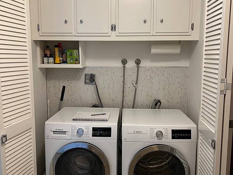 In-house Laundry with cupboards for storing cleaning supplies and detergents.