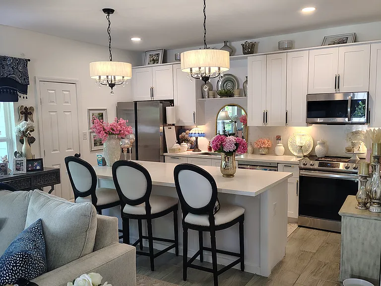 Full view of kitchen from living room with exquisite pendant lighting. Wall of windows on left side makes it feel like an amazing treehouse.