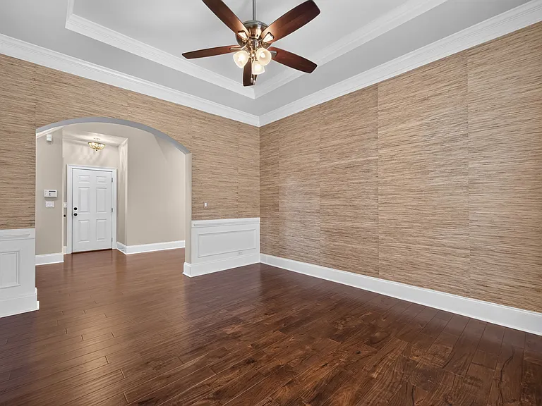 formal dining room with crown moulding, grass wall paper, and trey ceiling.