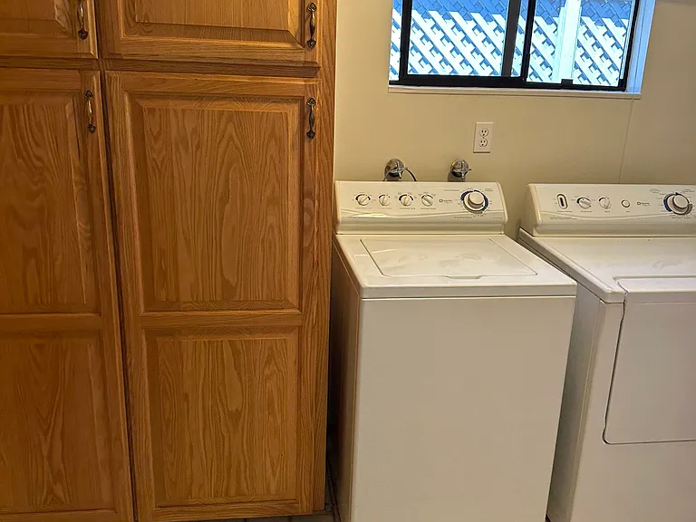 Large inside laundry with more pull-out oak storage cabinets.