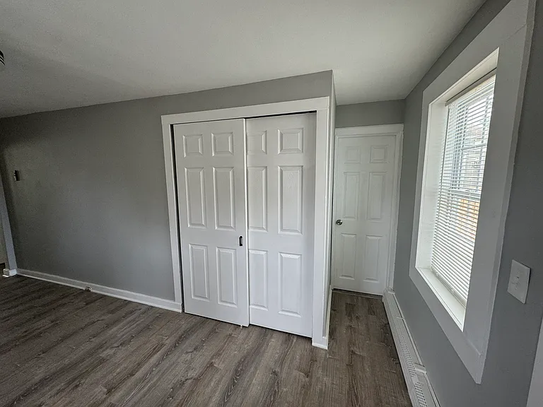 Washer/dryer behind doors, short walkway to bathroom closed door.