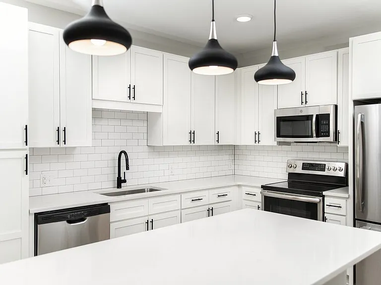 Kitchen with white quartz countertops, white cabinetry, and stainless steel appliances