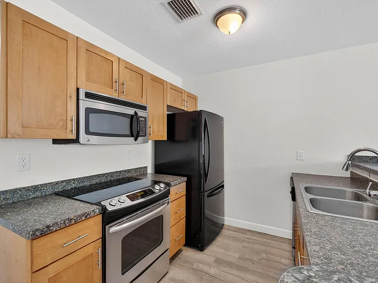 Kitchen complete with oven, stove, built in microwave, refrigerator, freezer, dishwasher, and garbage disposal