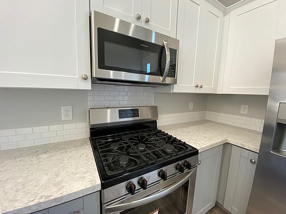 Subway tile backsplash at counters. White upper cabinets, grey lower cabinets - doors are popular "Mission style".
