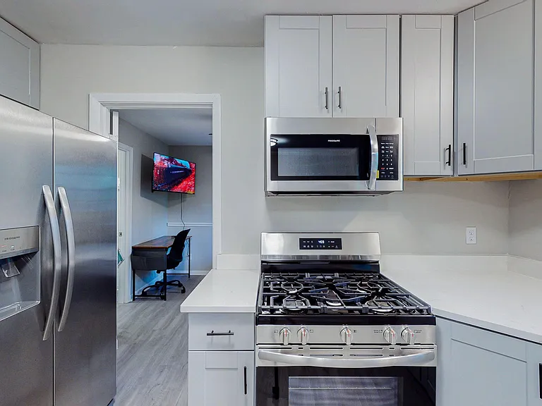 Updated kitchen with shaker cabinetry, quartz-style counters, and stainless steel appliances including gas range and microwav