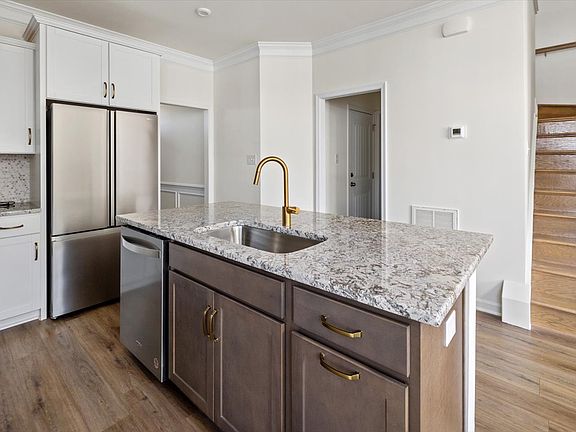 Kitchen with granite counters, penny tile backsplash, oven, microwave, dishwasher, refrigerator, deep stainless steel sink and large eat in bar area.